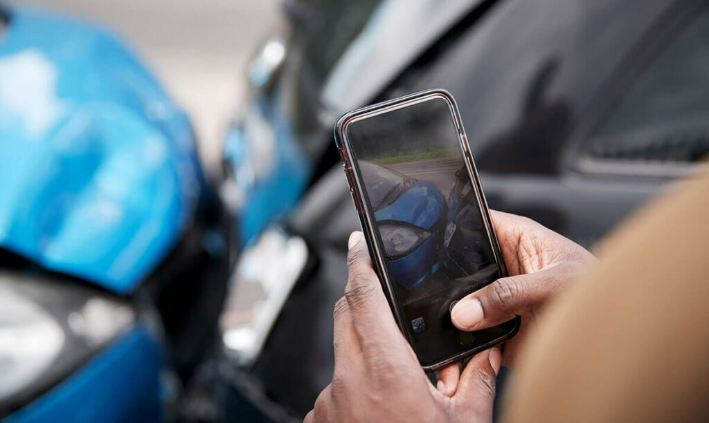 close up of a person using a phone to take a photo of a car accident